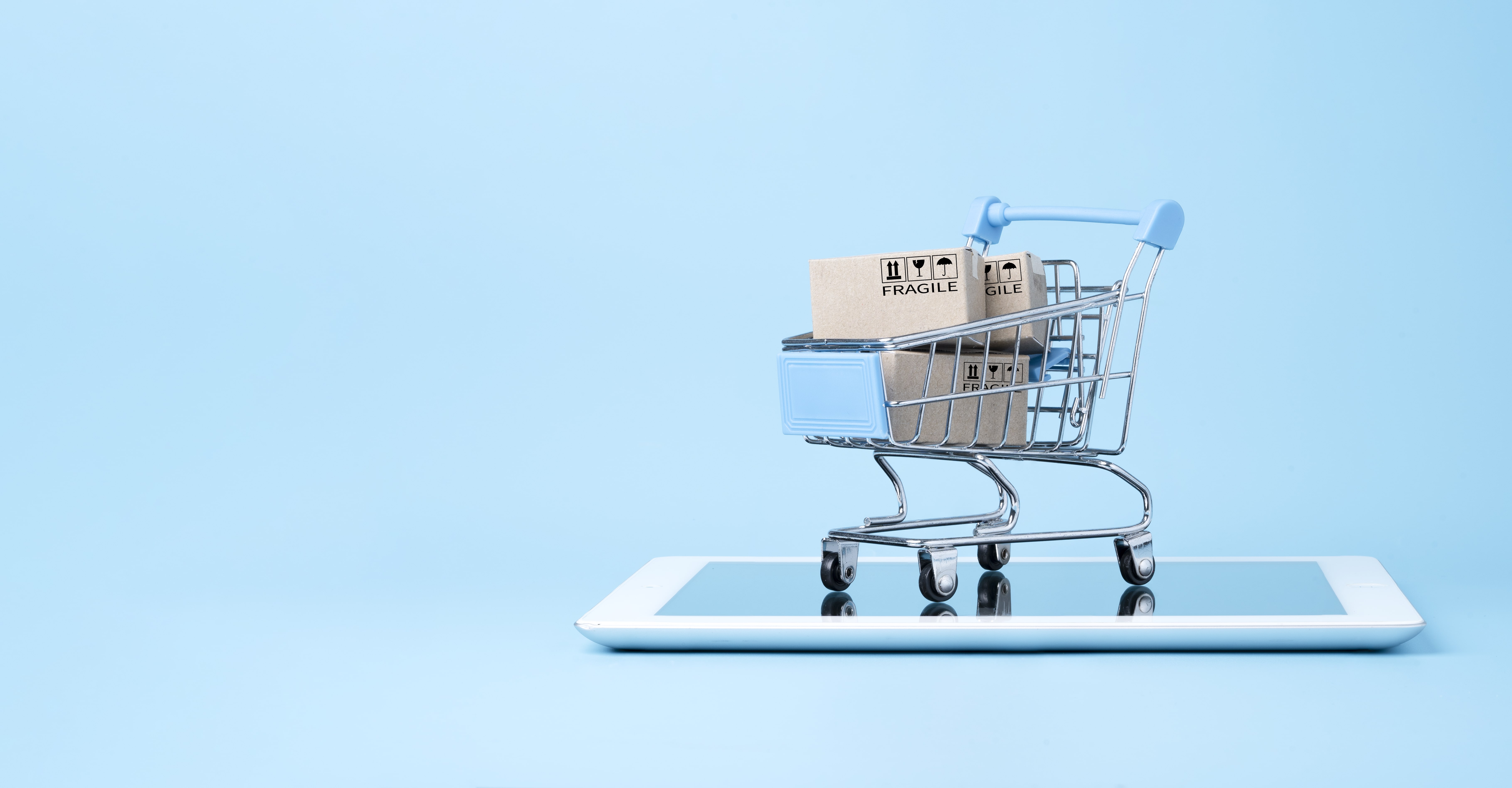 isolated-shipping-paper-boxes-inside-blue-shopping-cart-trolley-tablet-isolated-blue-min